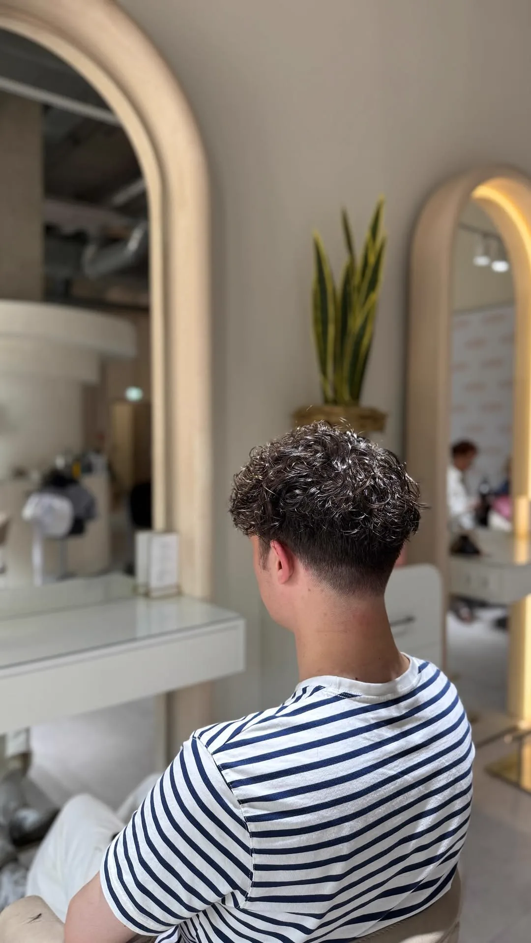Herrenschnitt mit lockigem Deckhaar, von hinten im Salon