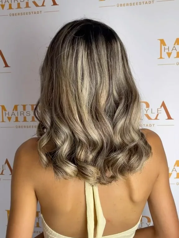 Blonder Balayage-Bob mit Wellen vor der Salonwand