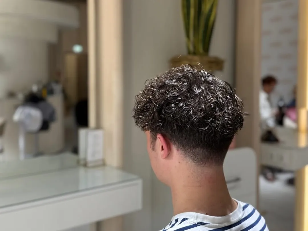 Herrenschnitt mit lockigem Deckhaar und kurzen Seiten, wie ihn eine Dauerwelle f&uuml;r M&auml;nner m&ouml;glich macht, im Salon Mira Hairstyle
