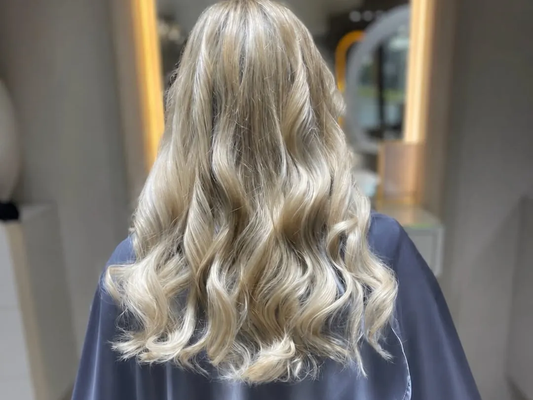 Helle, kühle Blondtöne in weichen Wellen, von hinten im Salon Mira Hairstyle